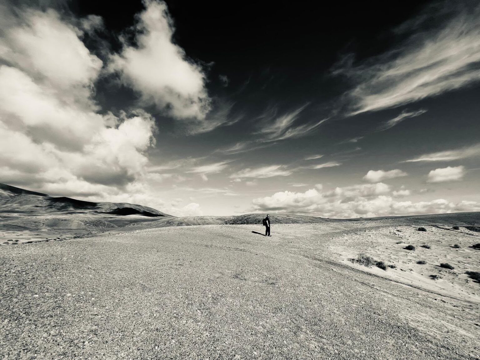 Schwarz-Weiß-Fotografie: einsame Person auf einem weiten Weg durch die Dünen